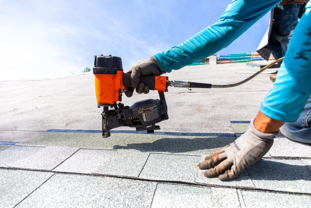 Roofer installing roof shingles with pneumatic roofing