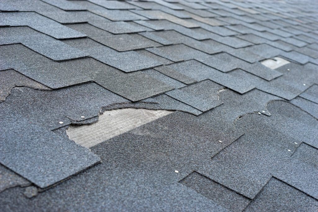 Сlose up view of asphalt shingles roof damage that needs repair